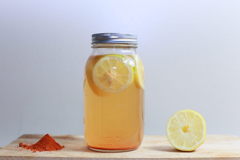 A jar with lid, containing lemonade and lemon slices.