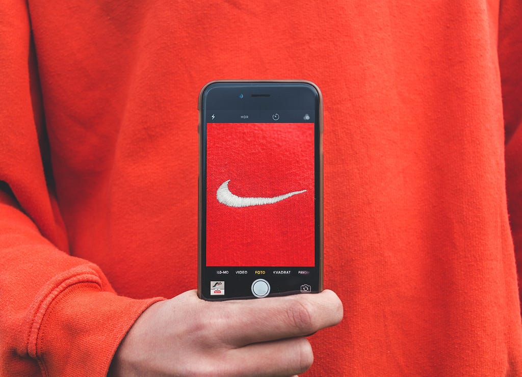 Someone holding a smartphone that shows the Nike logo on fabric.