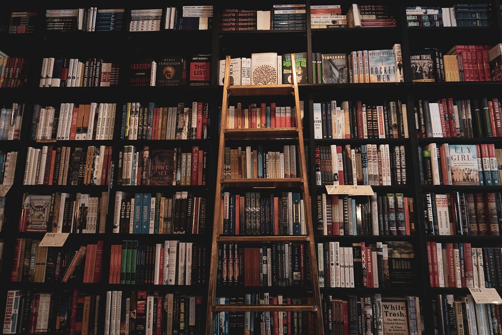 brown wooden ladder leaning on bookcase filled with books