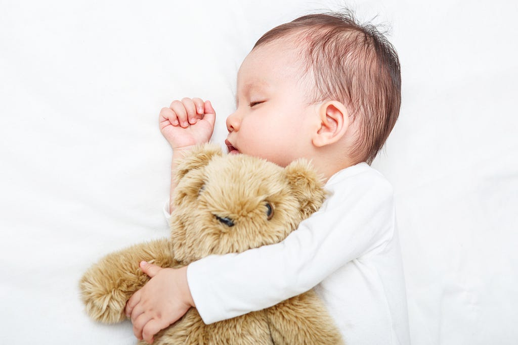Baby sleeping with her teddy bear, new family and love concept