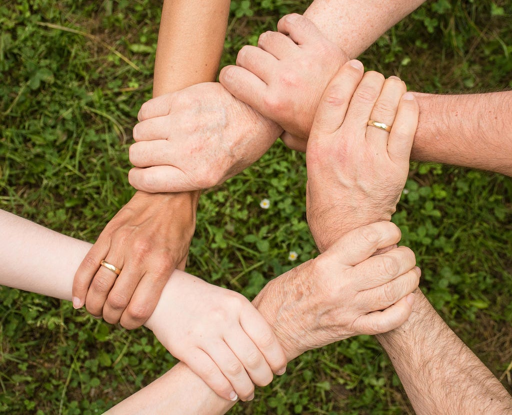 A group of people holding hands. Image courtesy Pixabay on Pexels.