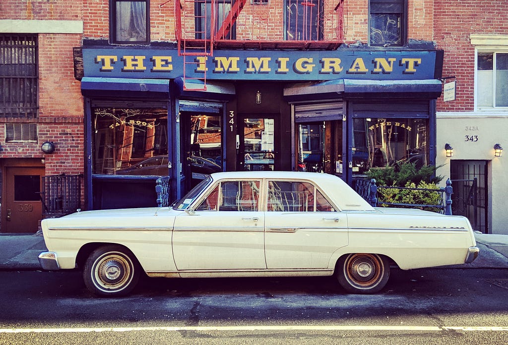 A classic car parked in front of the Immigrant wine and beer bar