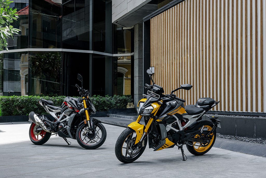 Two TVS Apache RTR 310 motorcycles parked outside of a building.