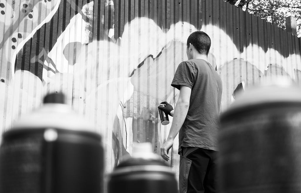 Photograph of a man spray painting a wall