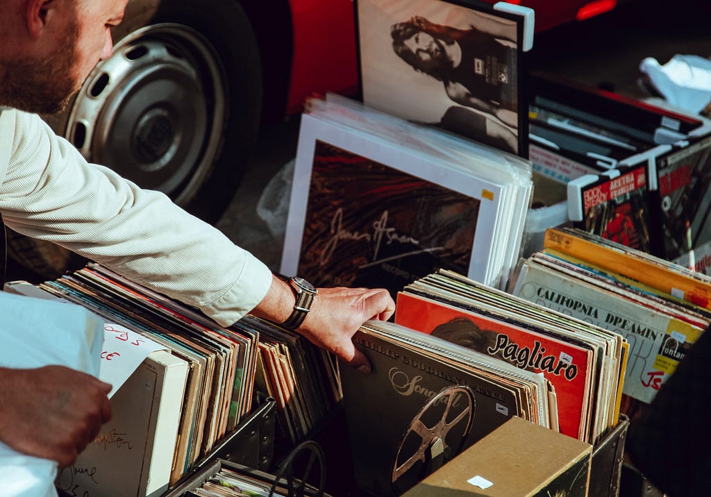 A man reaches for a vinyl record among a stack of albums.