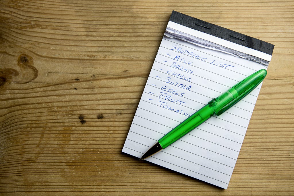 A shopping list of essentials made on a notepad.