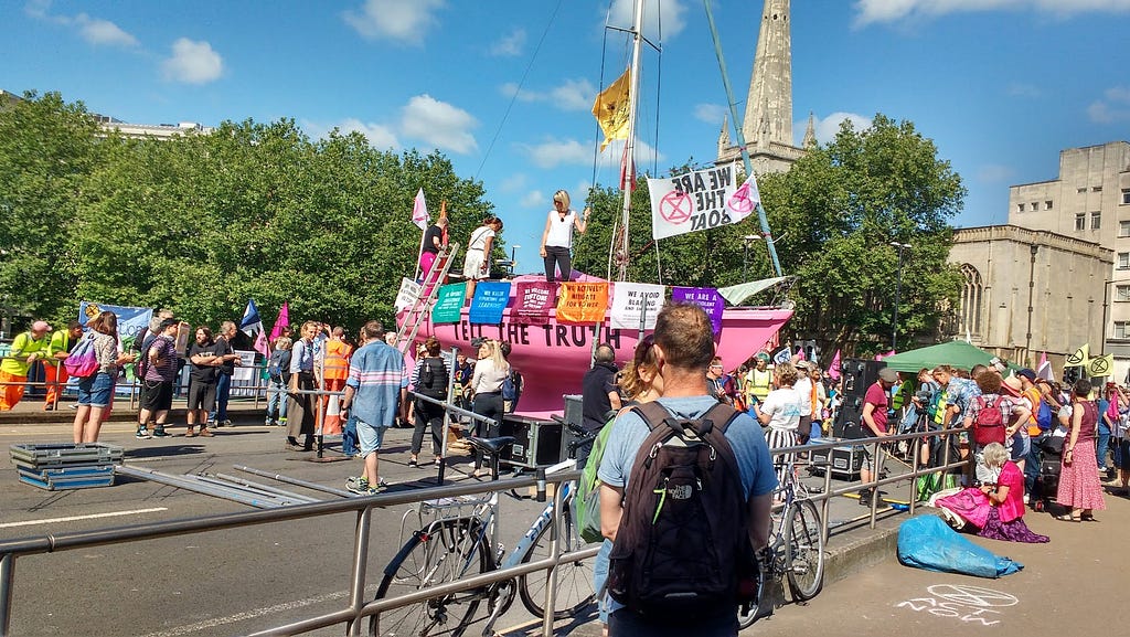 Extinction Rebellion protesters stand around a pink boat with ‘Tell The Truth’ written on it on Bristol Bridge