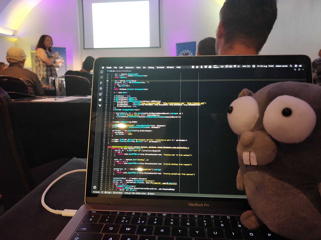 A stuffed toy gopher sits on a laptop during a conference talk.