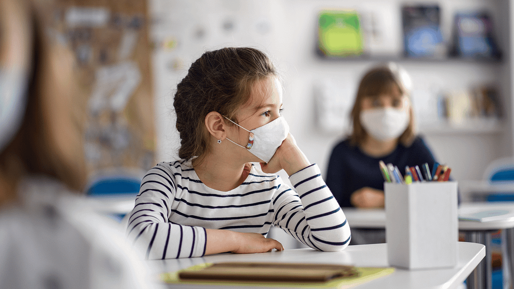 Little girl in school wearing a mask.