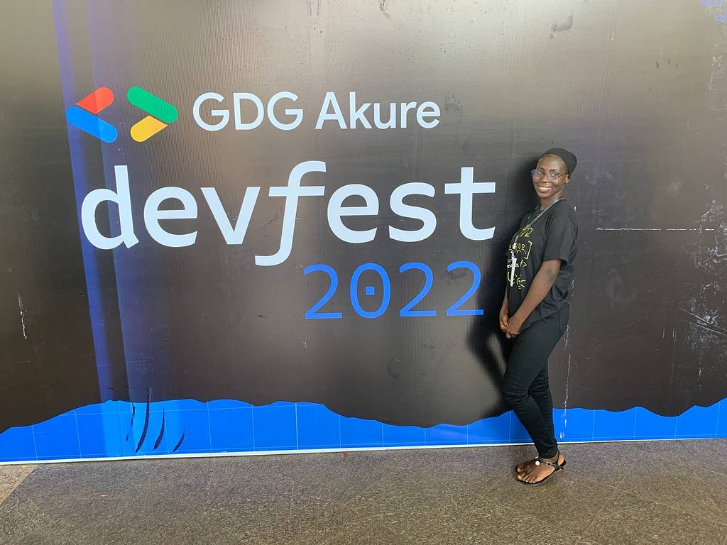 A picture of me standing in front of the Google developer group Devfest banner(Akure) 2022