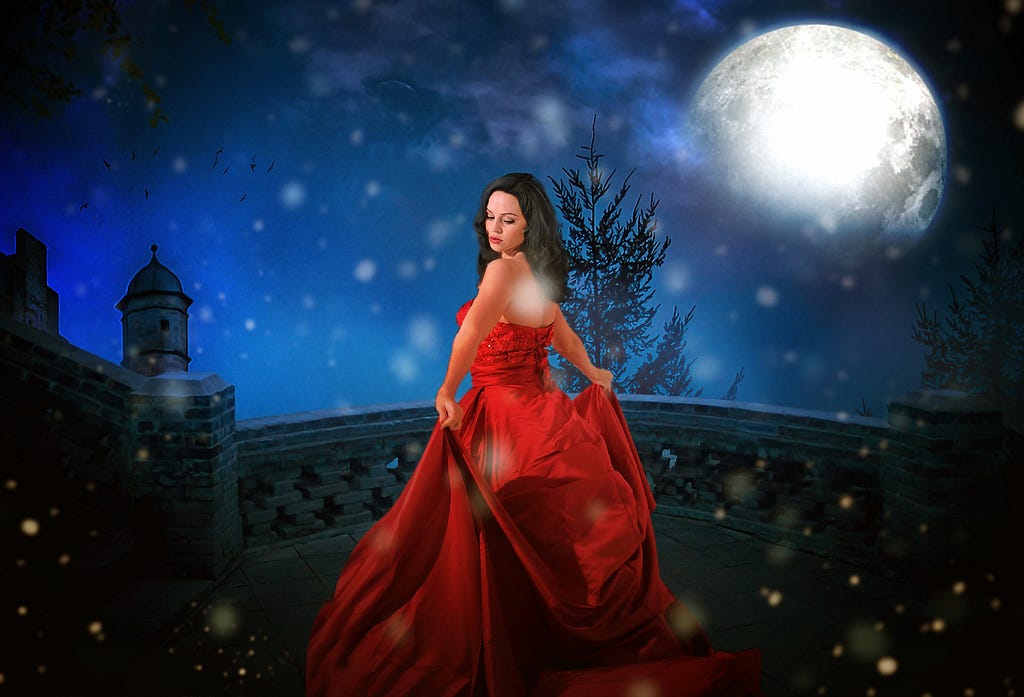 A woman in a red grown next to an old mansion house