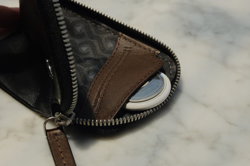 Coin pouch on a black Bellroy Card Pocket with an AirTag sticking out