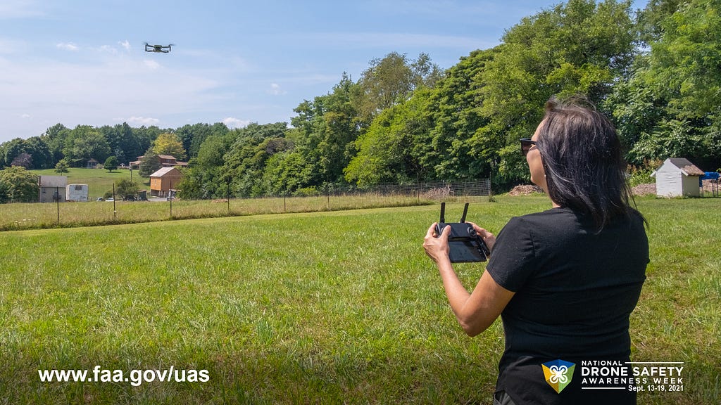 Woman flying drone over a field.