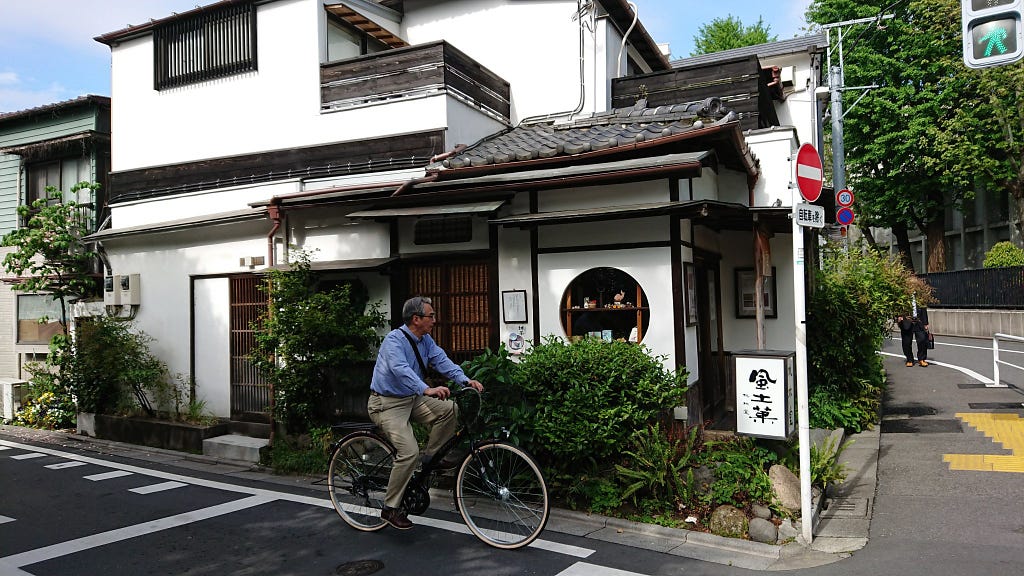 A middle-aged man in shirt and chinos rides his bike through a quiet old neighbourhood
