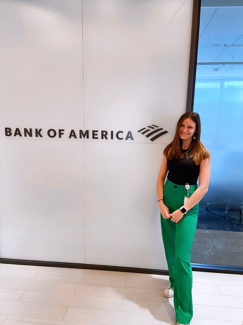 Reese smiles for a photo at the Bank of America office next to a sign with the company name