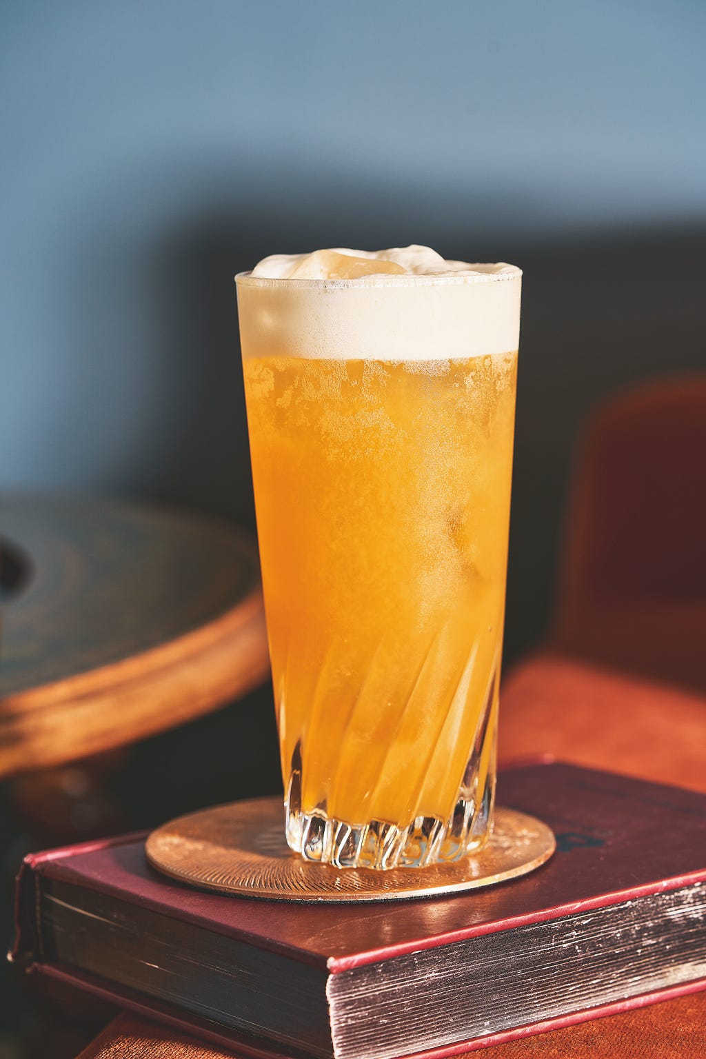 a glass of a sparkling amber cocktail with foam on top