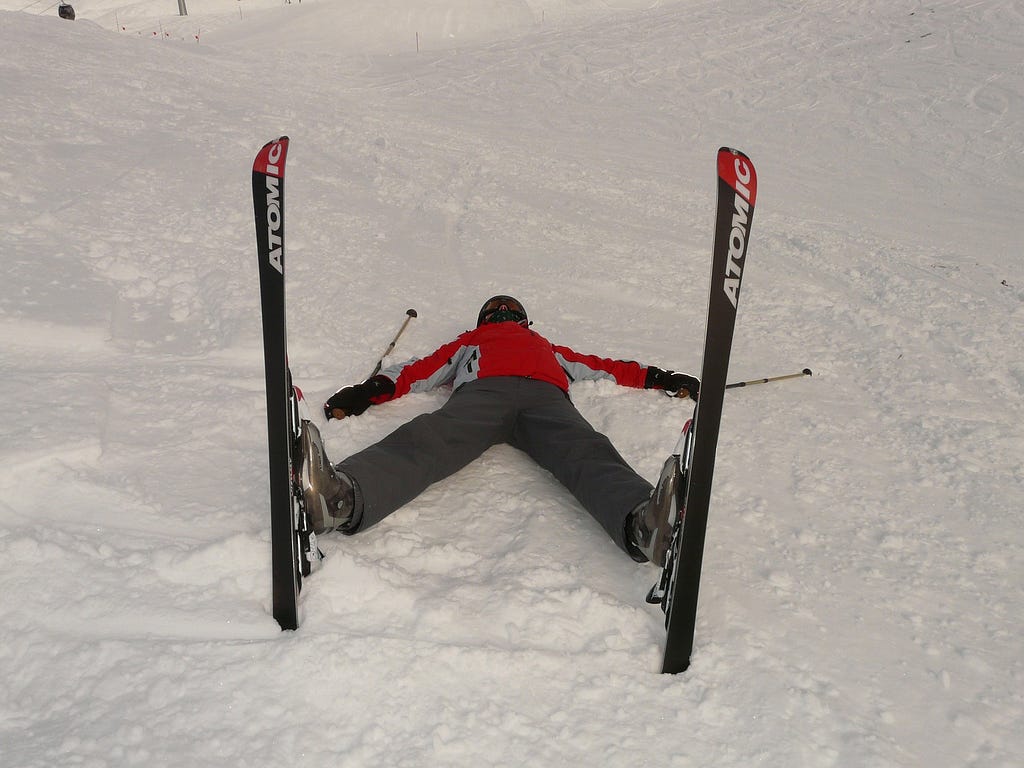 Skier laying on his back in the snow, spread-eagle and ski tips straight up