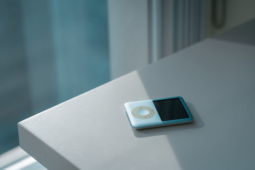 Blue iPod Nano 3rd Gen on table. Photo by Ruijia Wang on Unsplash.