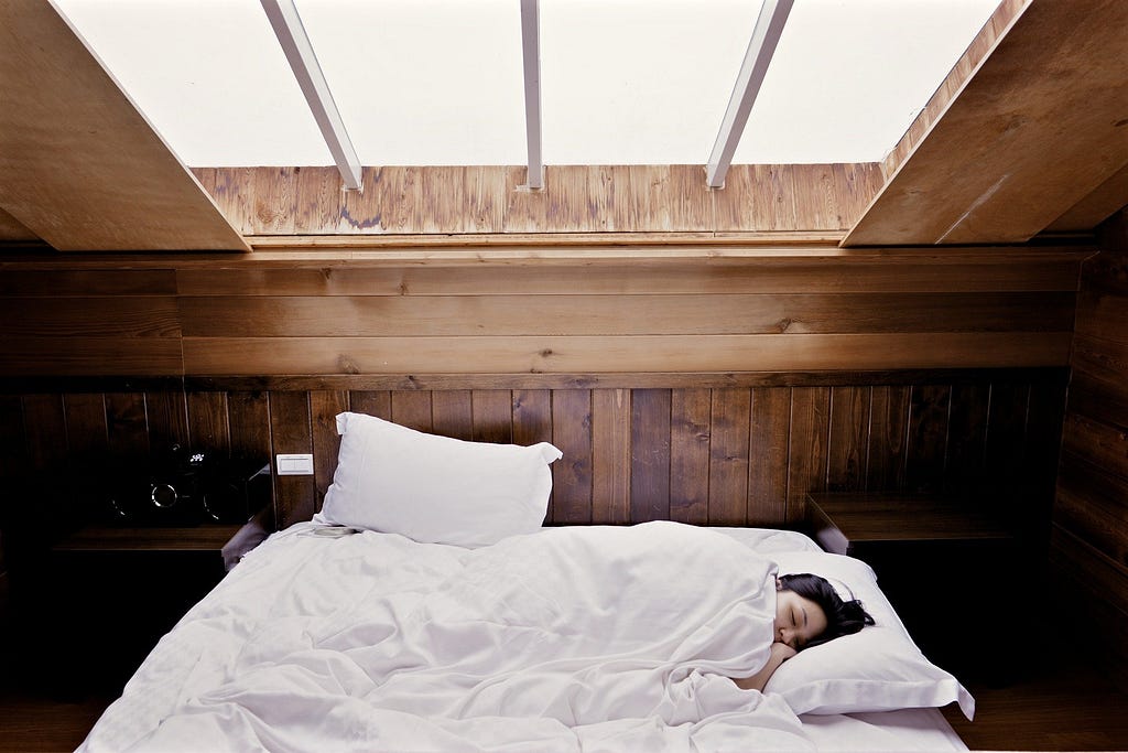 Rapariga deitada numa cama de lençois brancos
