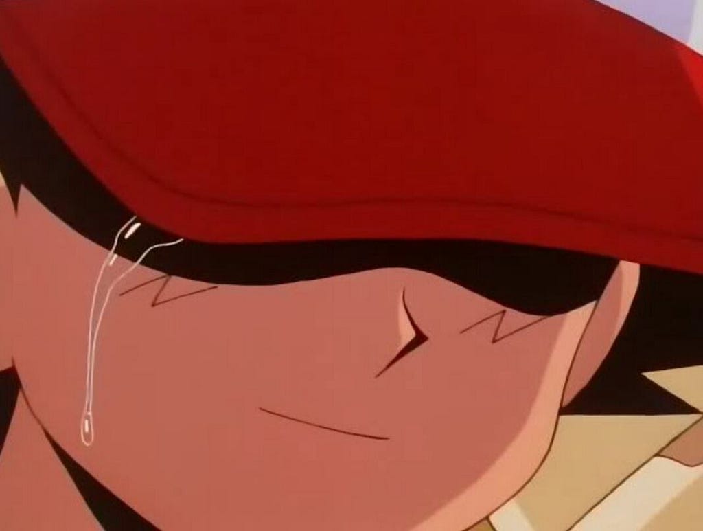 Ash, the original main character from the Pokemon series, sheds a single tear, his eyes hidden behind his red cap and a slight smile on his face
