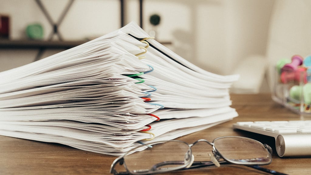 Reading glasses next to a stack of bound papers.