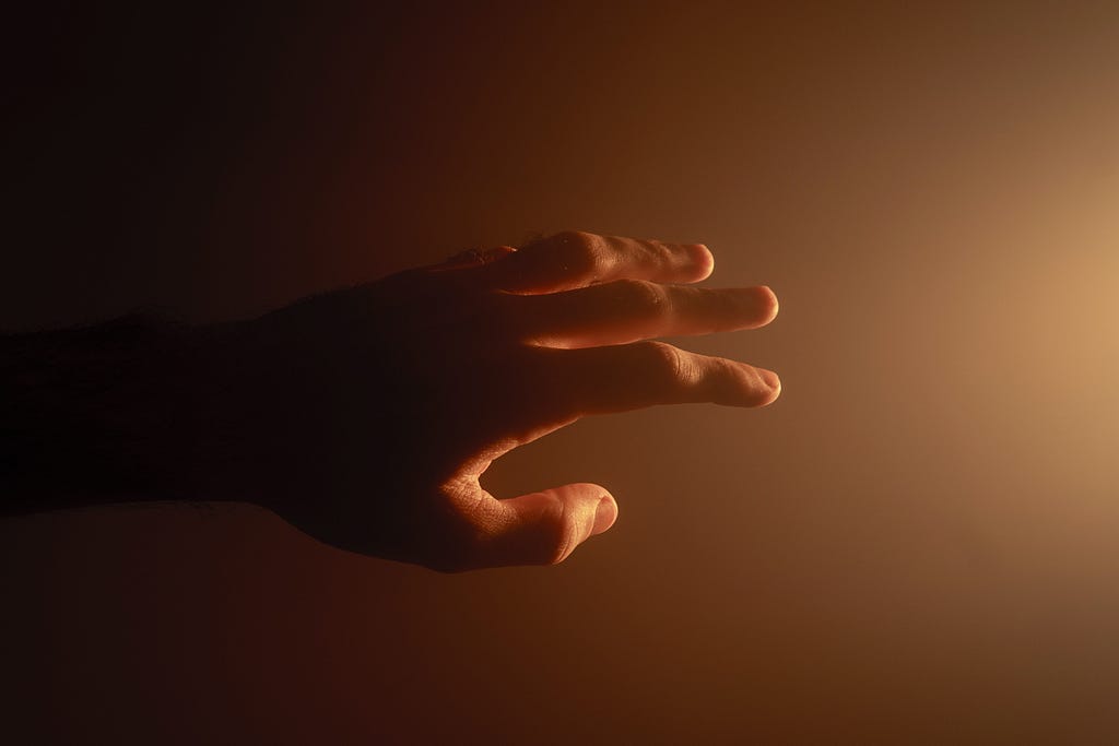 Hand reaching out towards light.