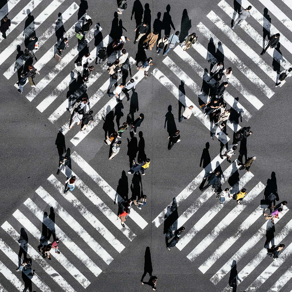 Picture from above of people crossing a 4 way crosswalk