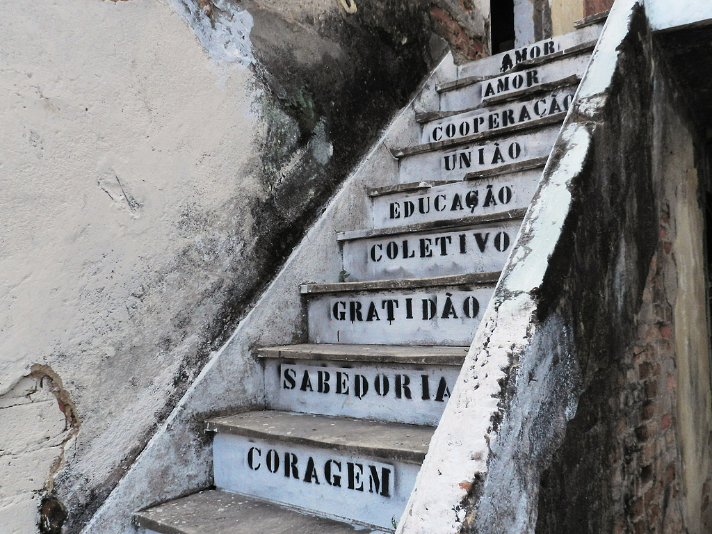 Degraus de escada decorados por stencil com palavras como amor, cooperação, união educação, coletivo e gratidão.
