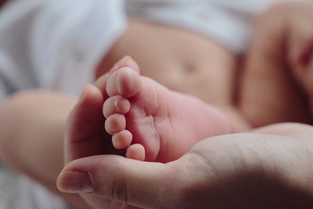 Hands holding new borns baby feet.