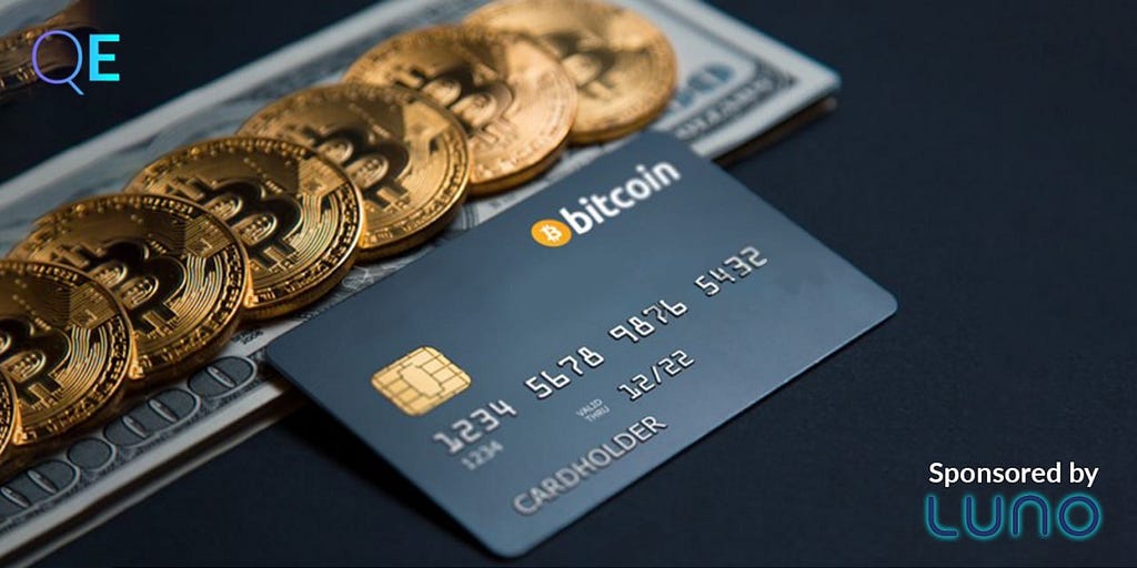Physical units of bitcoin on a fiat bill, next to a bitcoin credit card