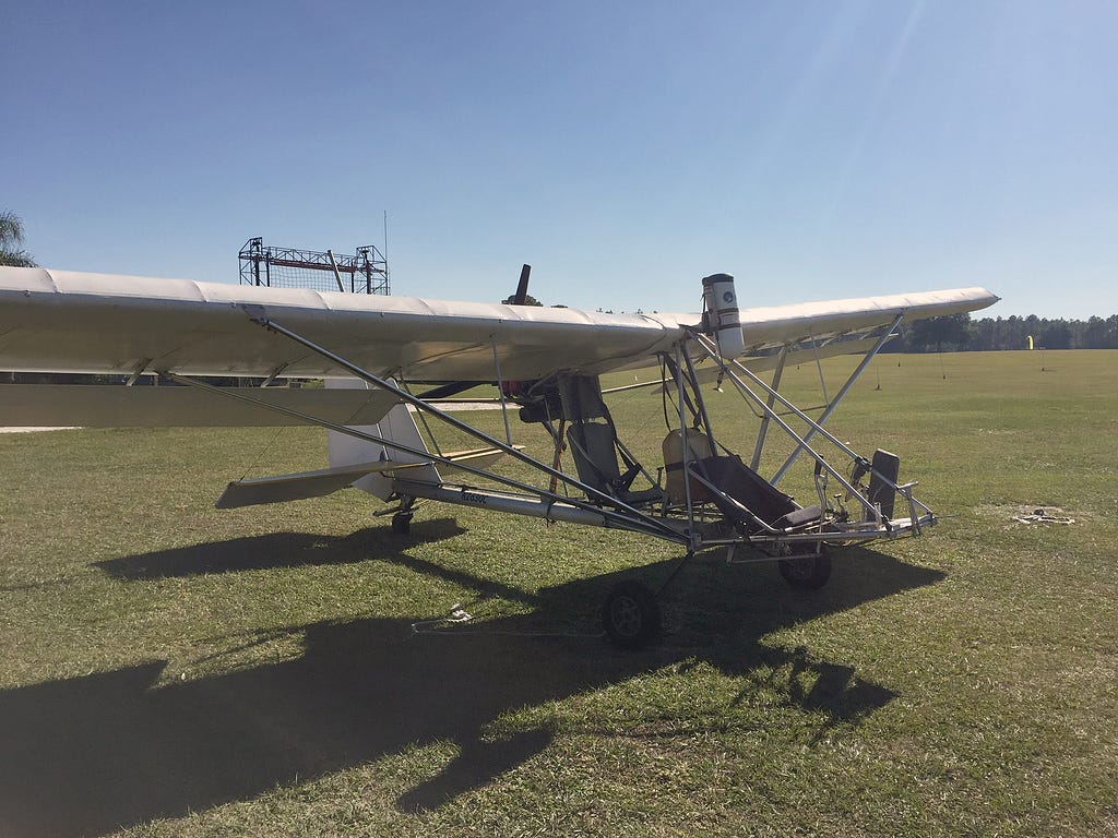 A white ultralight airplane on a grassy field