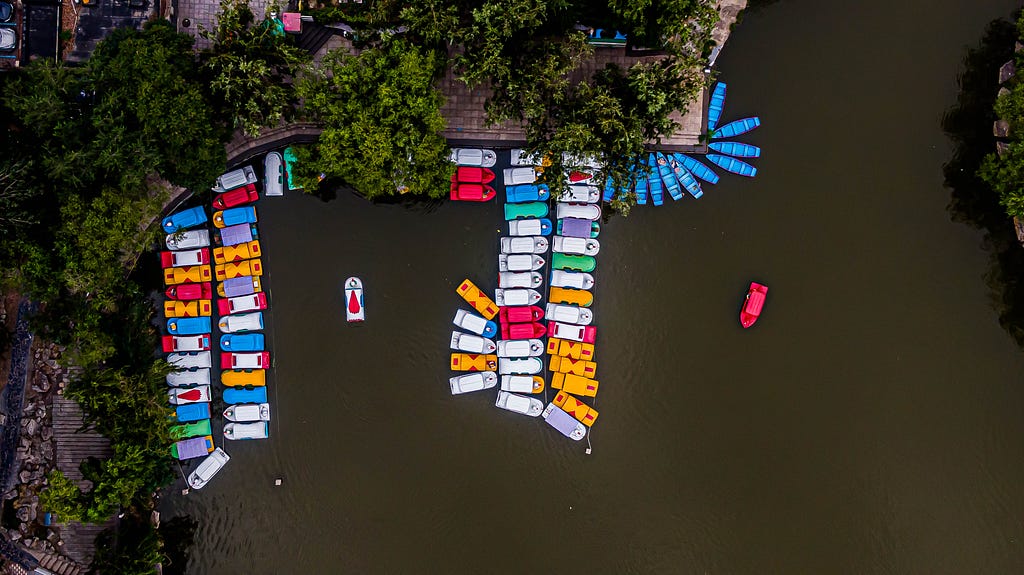 A look down at a marina, lines of colourful boats in water.