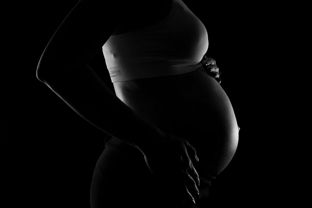 pregnant women’s belly, dark background.