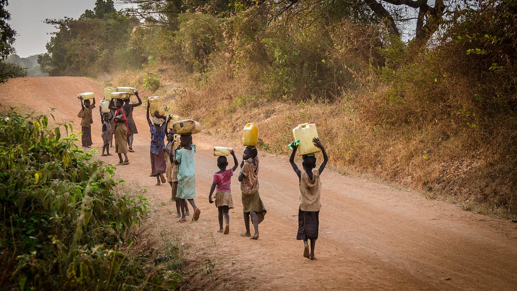 People in Africa walking across a road carrying water