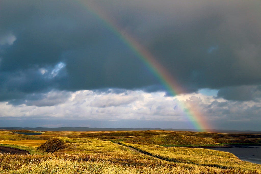 rainbow arches over golden tundra