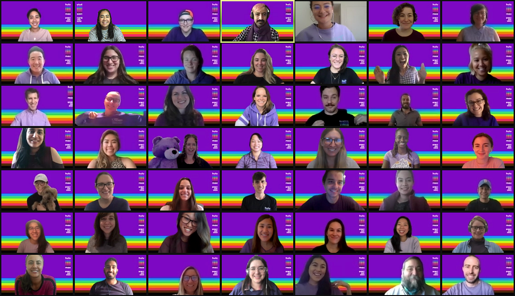 Screenshot of a Zoom meeting with 50 team members, smiling, with purple, Spirit Day backgrounds.