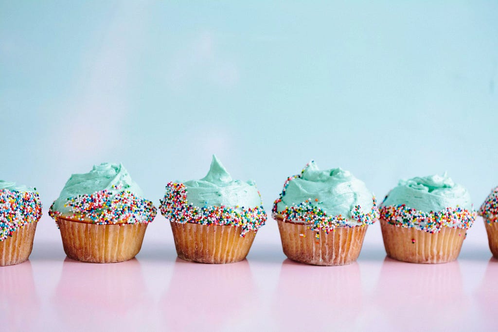 A row of sky blue cupcakes decorated with sprinkles