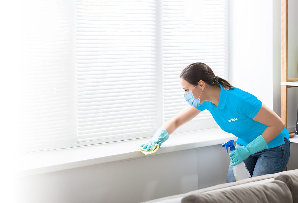 A professional Justlife cleaning agent cleans the window ledge