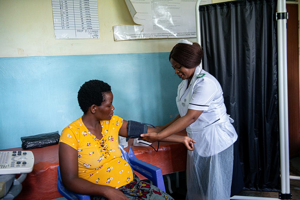 A nurse adjusts a blood pressure monitor on a patient’s arm.