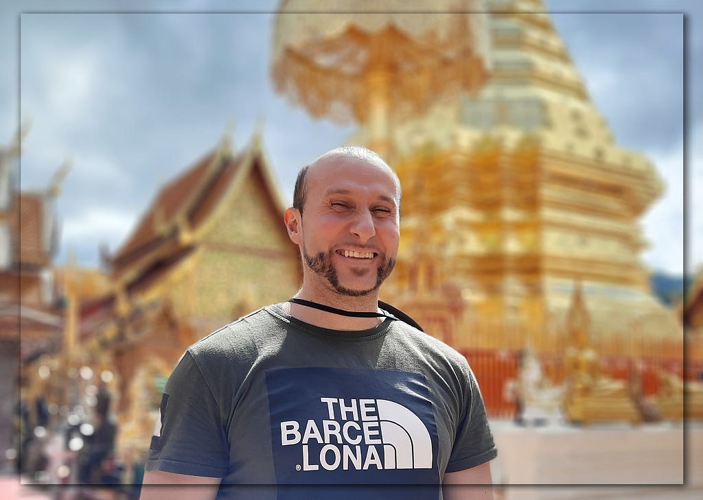 A photograph of me candidly smiling. Behind me is the famous giant gold pagoda found at Wat Phra That Doi Suthep (temple).