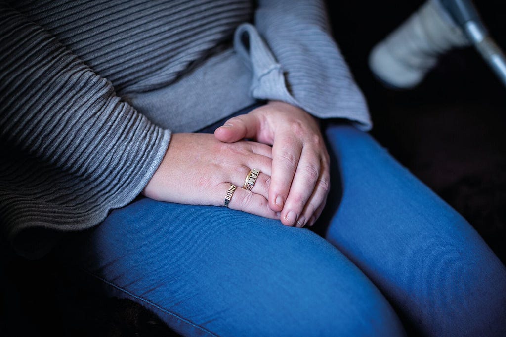 Hands crossed over on the lap of a victim-survivor of economic abuse