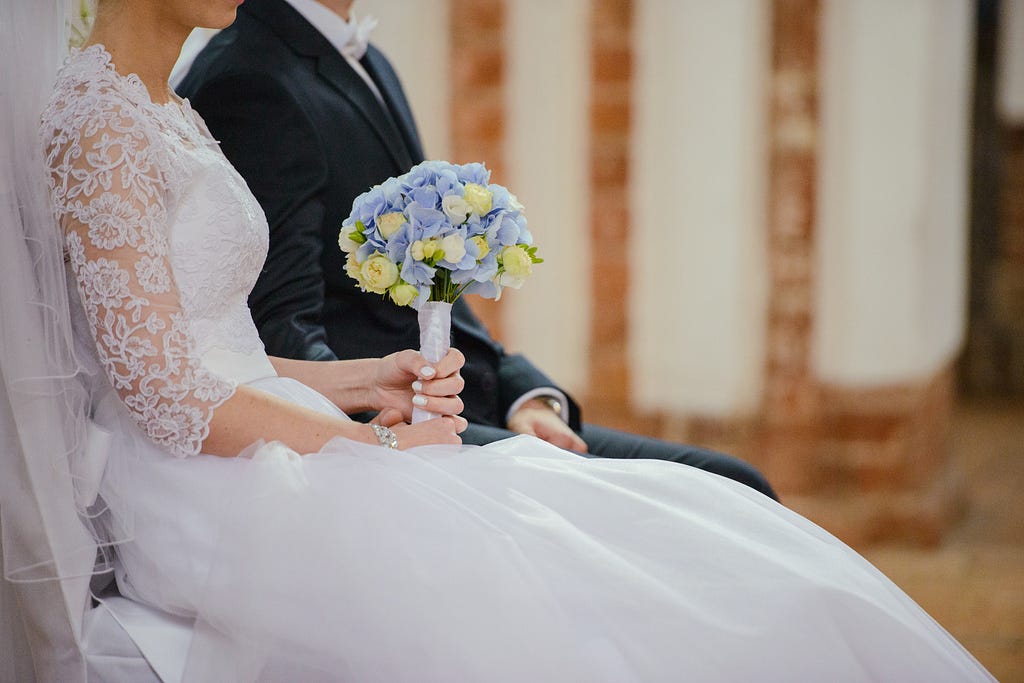 Picture of a bride and groom sitting, with the bride holding a beautiful bouquet