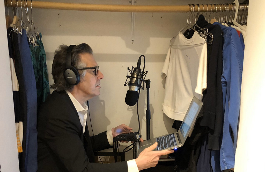 Photo of Ira Glass in a closet at home with his podcasting equipment