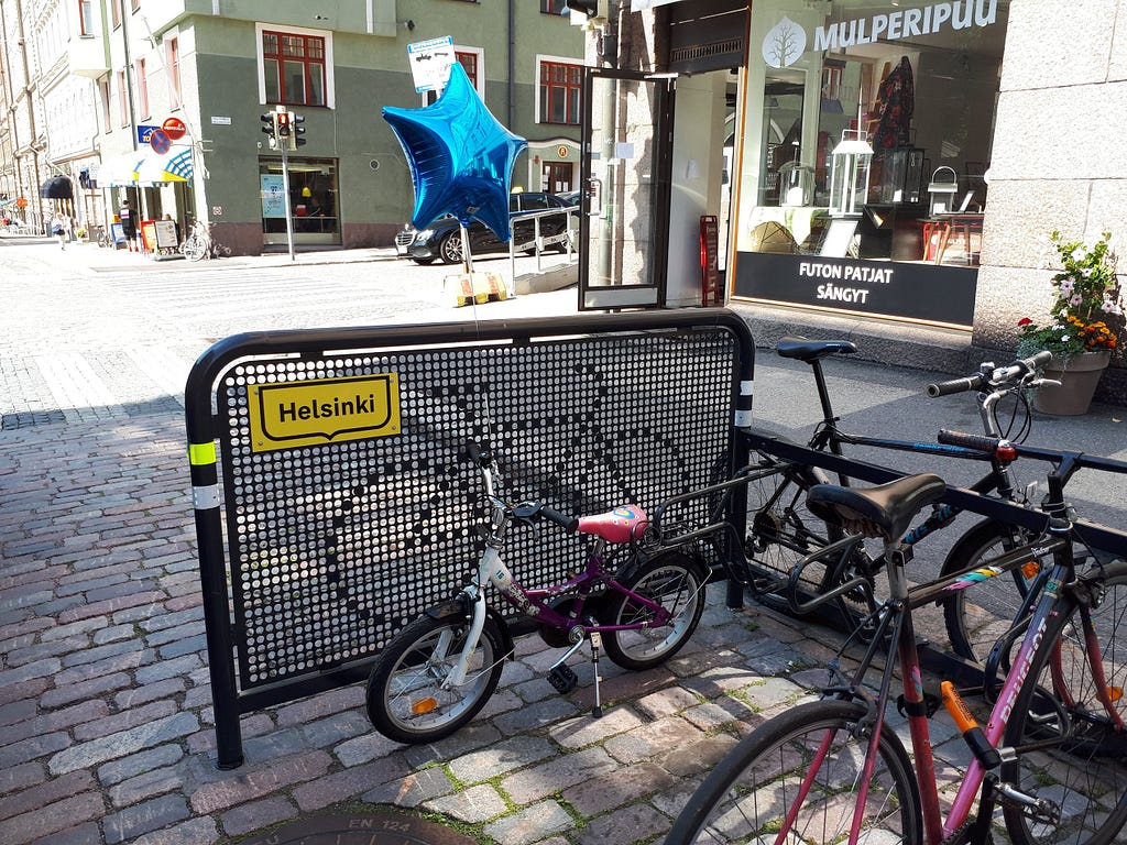 Children’s bike with a balloon attached, parked at a Helsinki street side