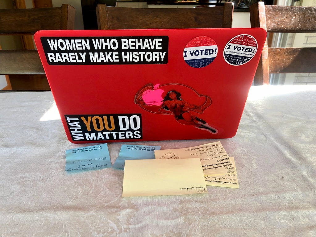 Photo of red laptop with blue and yellow post-it notes piled in front of it.