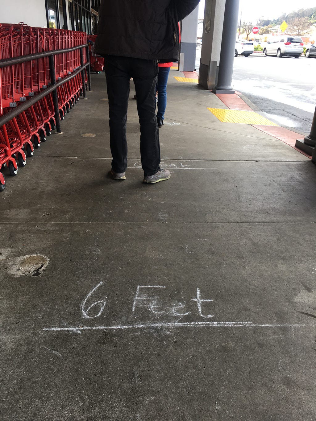 Sidewalk with 6 Feet written between shoppers outside Trader Joe’s