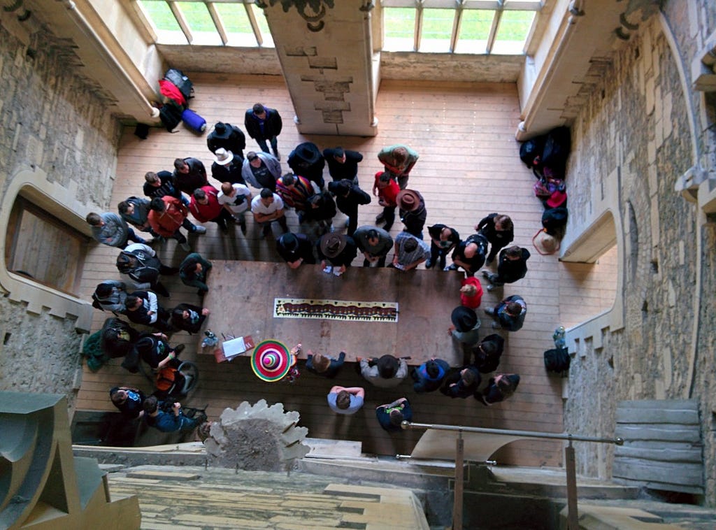 A group of people crowd around a long table to discuss strategy at the start of an immersive learning activity.