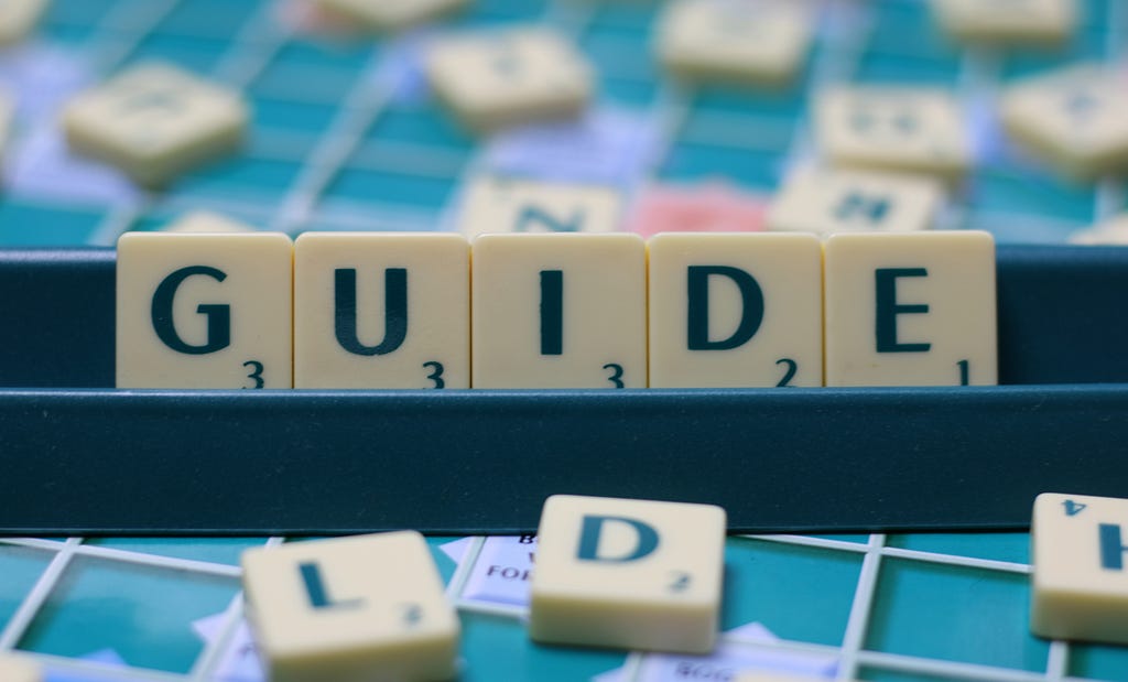 Scrabble bricks forming the word “GUIDE” on the rack.