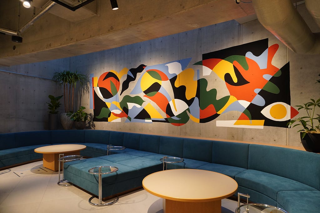 A lounge area with colourful wall paintings behind sitting area