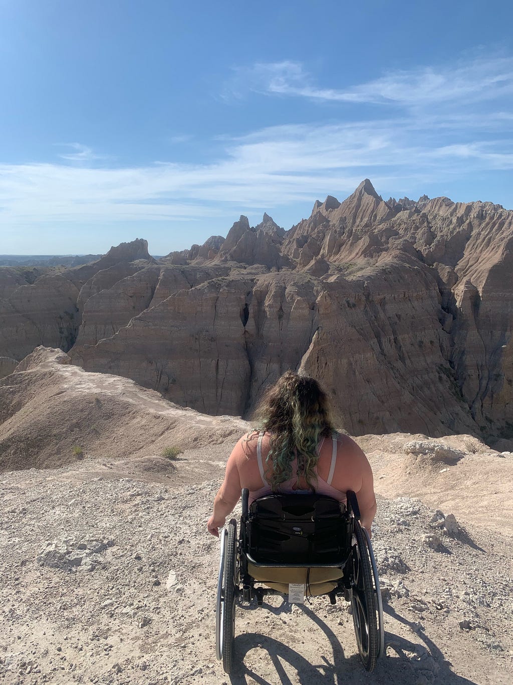 Woman in wheelchair facing away from camera looking at mountains in Badlands National Park